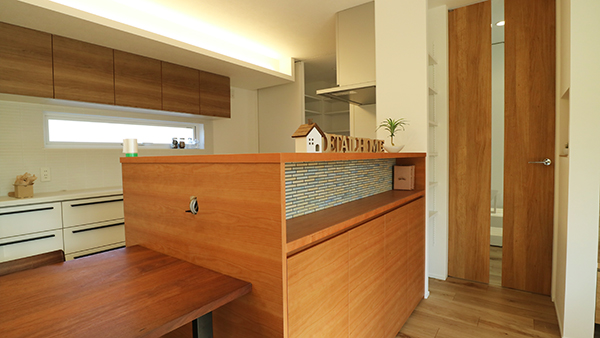 キッチン背面収納は家具としてリビングを演出。食器棚上部の間接照明がアクセント