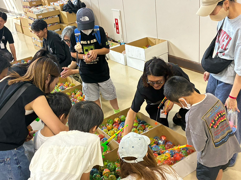 カラフルなおもちゃが並ぶ縁日コーナーを楽しむ子どもたち