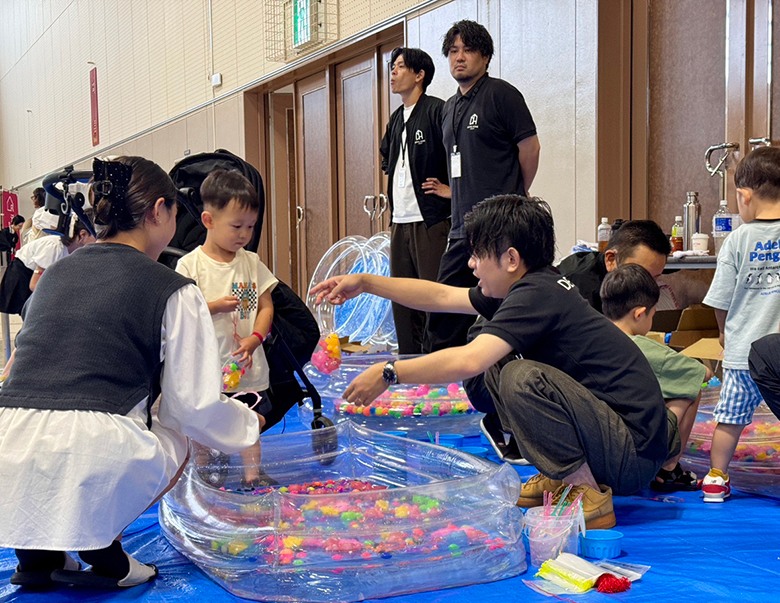 水に浮かぶおもちゃをすくって楽しむ子どもとスタッフ